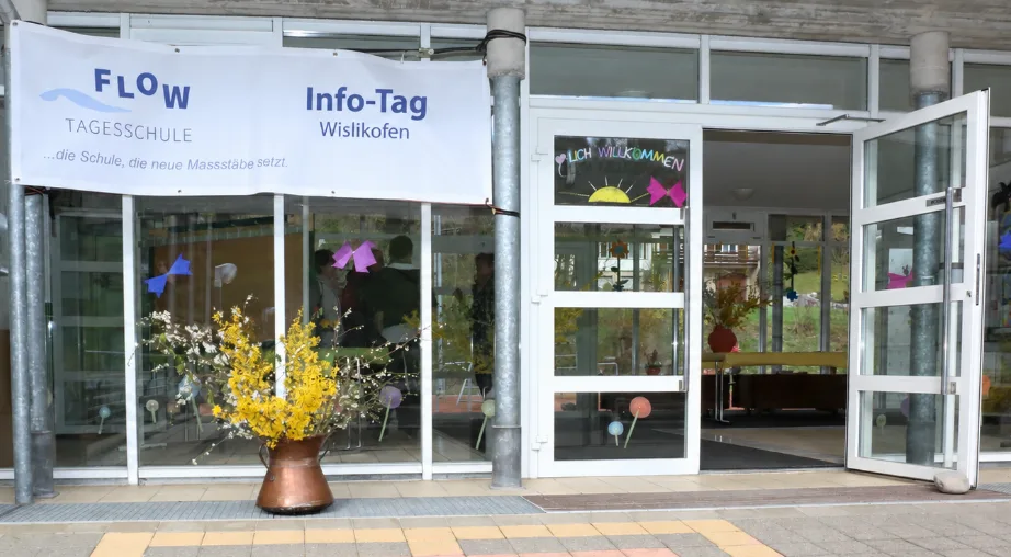Offene Schulhaustür mit Banner "Info-Tag".