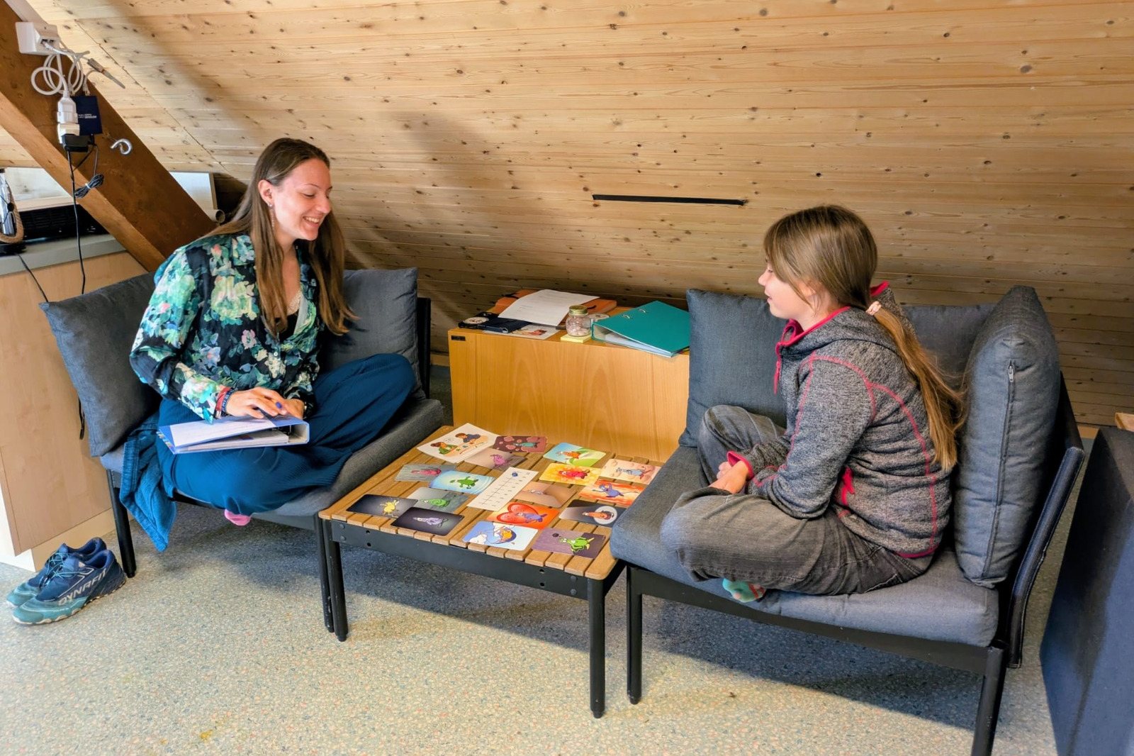 Coachinggespräch: Eine Erwachsene und ein Mädchen sitzen sich gegenüber, auf dem Tisch liegen Bildkarten