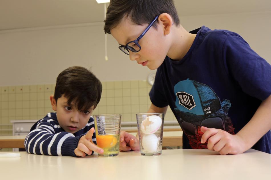 Zwei Jungen experimentieren mit Eiern und Gläsern
