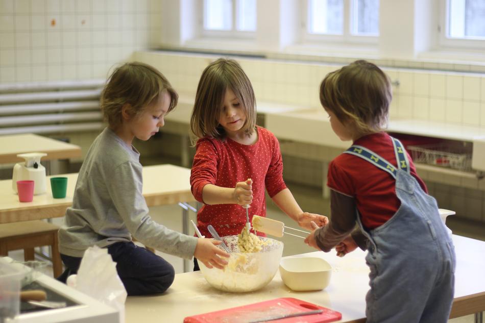 Kinder rühren in der Schulküche einen Teig